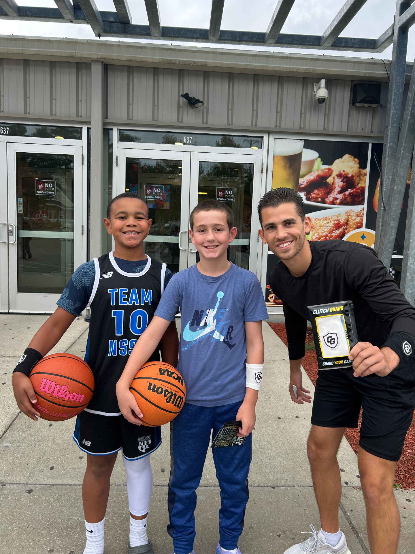 Clutch Guard founder with two young basketball players wearing Clutch Guard wristbands