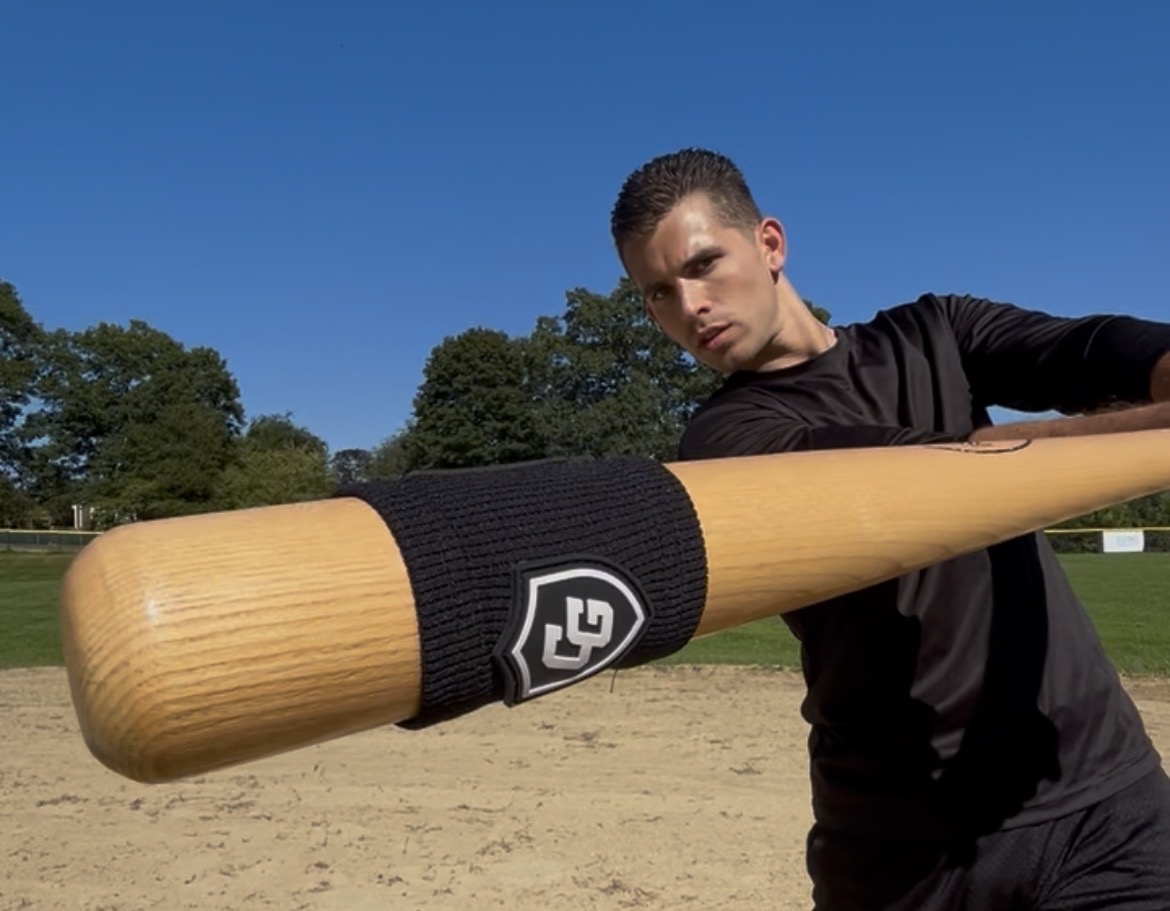 Clutch Guard founder pointing a banded bat at the camera on a baseball field